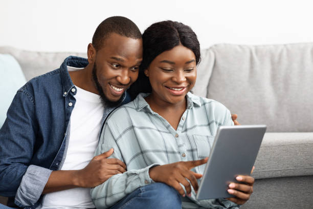 istock Black Happy Millennial Couple Using Digital Tablet Together While Relaxing At Home 1342218470