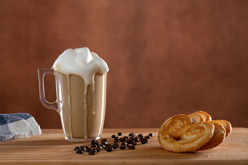 Cappuccino cup with milk froth and palmier for breakfast