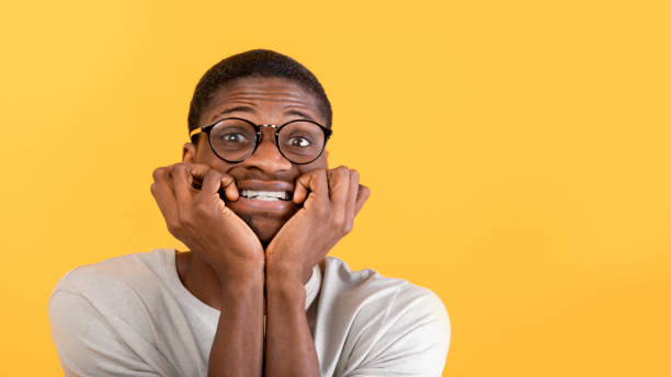istock Stress control concept. Afraid black man biting nails with worry, looking at camera over yellow background, panorama 1342222451