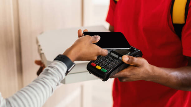 istock Unrecognizable Female Paying Deliveryman For Pizza With Cellphone Indoor 1342222484