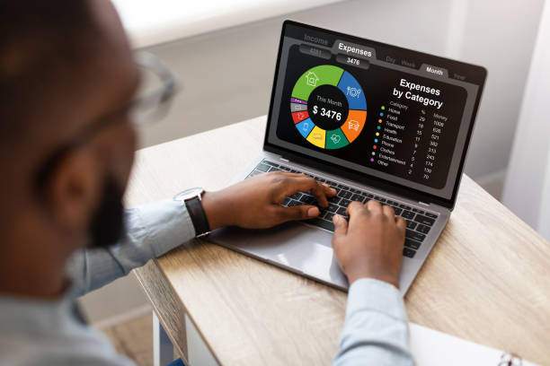 hombre de negocios negro usando computadora portátil, calculando el presupuesto familiar - persecución fotografías e imágenes de stock