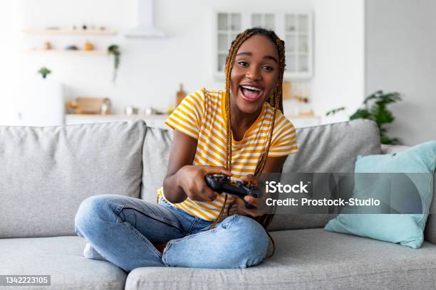 Joyful black woman playing video games at home