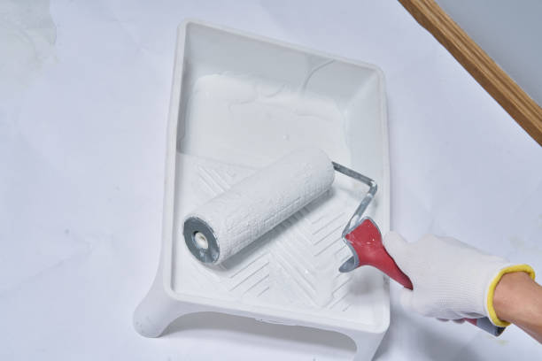 istock A hand in an white glove holds a paint roller in white paint 1342223153