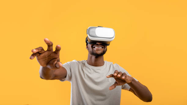 istock Virtual experience. Happy african american man wearing VR headset, touching air while playing video game 1342223176