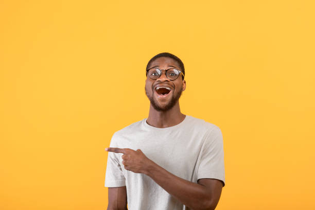 istock Surprised african american man pointing aside at blank space and looking at camera over yellow studio background 1342223482