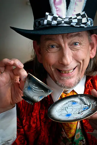 Mad Hatter looking at camera while holding ornate cup and saucer. Initial Rating 5! Thank you, iStock