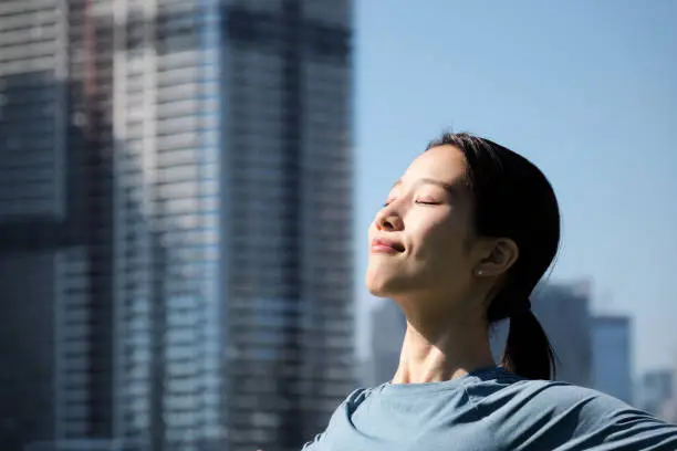 Asian young woman doing relaxation exercise in office park