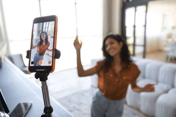 istock Young female influencer recording video content, dancing on camera at home, selective focus of smartphone on tripod 1342226934