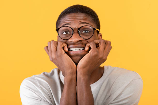 istock African american man biting nails in panic on yellow studio background. Horrified black guy feeling afraid or nervous 1342227048