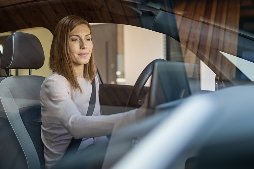 Smiling mature woman using global positioning system while driving her car.