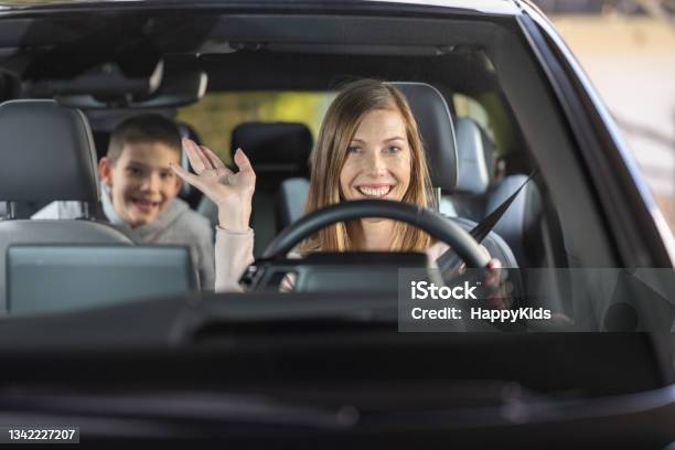 Mature Woman Waving Hand Inside Car Before Trip Stock Photo - Download Image Now - Driving, Car, Front View