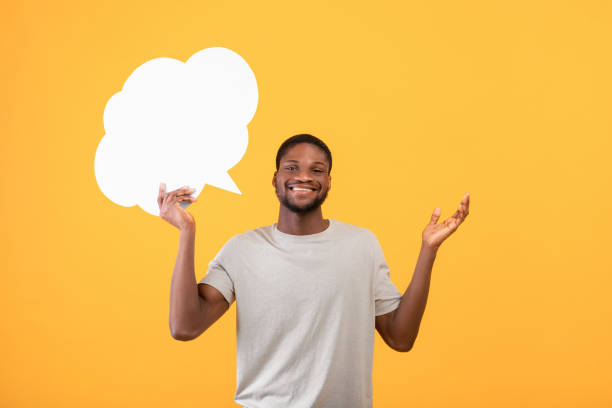istock Smiling black man holding blank speech bubble above his head over yellow background, mockup for your ad or design 1342228730