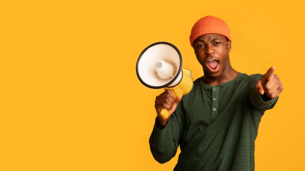 istock Attention. Emotional Black Guy With Megaphone Shouting And Pointing Finger At Camera 1342229017
