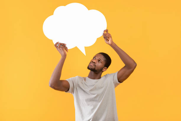 istock Thoughtful black man holding empty speech bubble over yellow studio background, free space for your ad design 1342229237