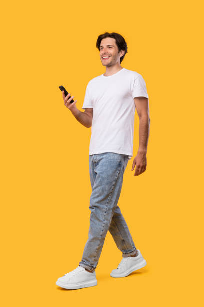 istock Young bearded man walking with cellphone isolated on yellow background 1342229263