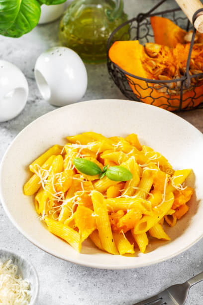 istock Neapolitan pasta penne rigate with pumpkin in a ceramic plate on a light gray culinary background close-up. Traditional Italian cuisine 1342230111
