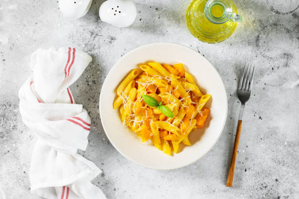 istock Neapolitan pasta penne rigate with pumpkin in a ceramic plate on a light gray culinary background top view with copyspace. Traditional Italian cuisine 1342230115