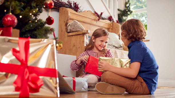 istock Two Excited Children Shaking And Feeling Presents Under Christmas Tree At Home 1342230192