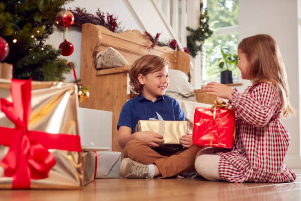 istock Two Excited Children Shaking And Feeling Presents Under Christmas Tree At Home 1342230226