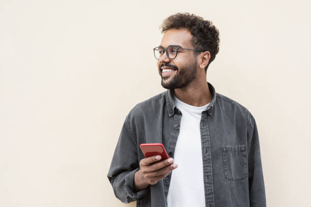 beau jeune homme utilisant un téléphone intelligent - men portrait smiling isolated photos et images de collection