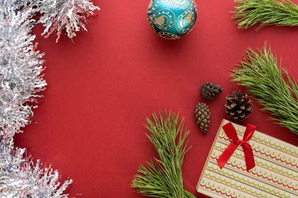 istock Christmas composition. A box with a gift and spruce branches on a red background. Spruce cones and Christmas decorations. Flat lay, top view, space for text 1342231510