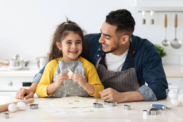 istock Happy Little Arab Girl Enjoying Baking With Dad In Kitchen 1342231652