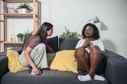 Two young women college roommates or coworkers argue about rent and expenses for the apartment