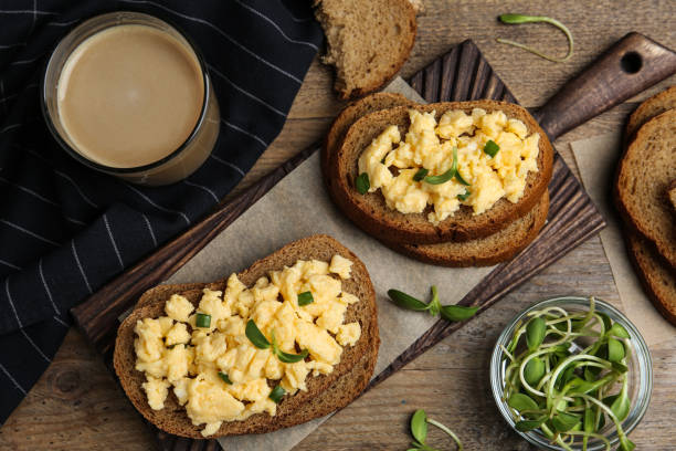 istock Tasty scrambled egg sandwiches served on wooden table, flat lay 1342235243
