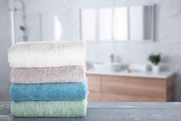 istock Stack of fresh towels on grey wooden table in bathroom. Space for text 1342235258