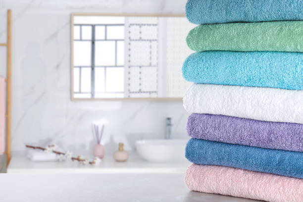 istock Stack of fresh towels on light grey table in bathroom. Space for text 1342235328