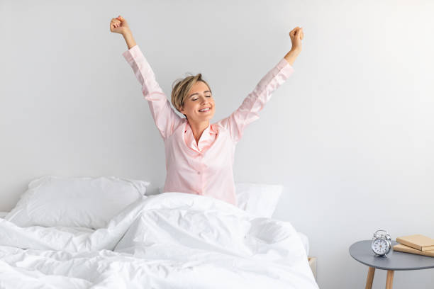istock Peaceful woman stretching arms sitting on bed 1342236315