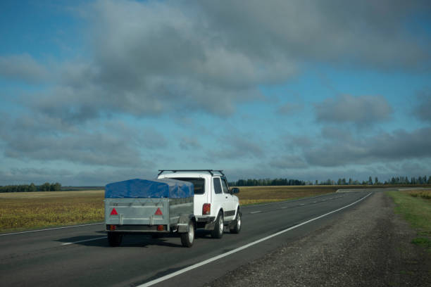 l'auto con un rimorchio si muove su una strada - vehicle trailer foto e immagini stock