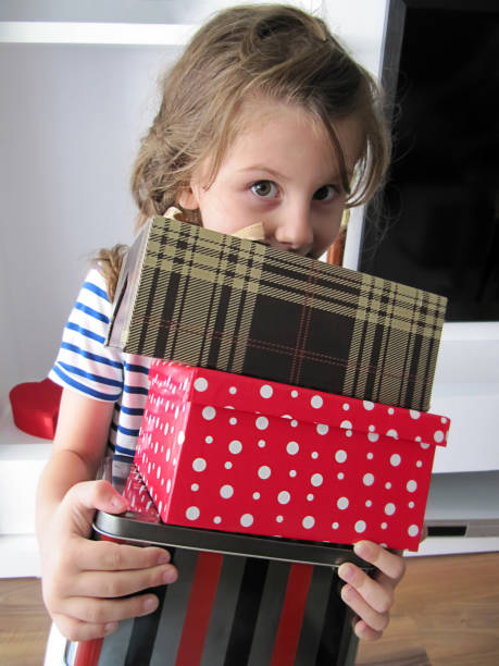 istock Little cute girl smiling and holding present boxes 1342239957