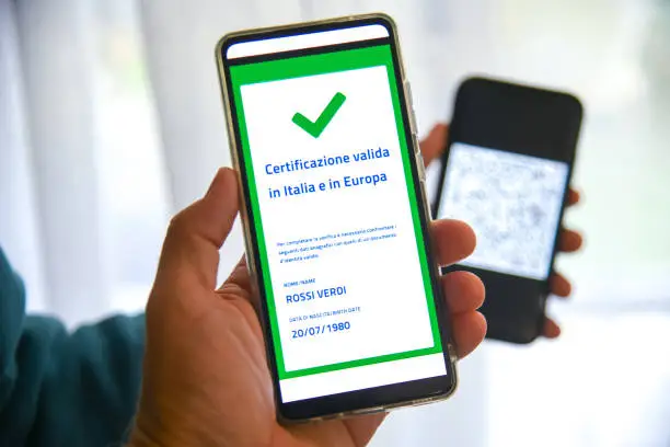 Photo of Checking the green pass on smartphone. Required for indoor tables in bar and restaurants, events and to access workplaces and company canteens. Valid certification.  Milan, Italy - September 2021