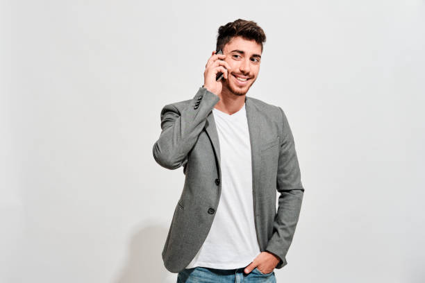 MR_Arturo.jpg Happy young man wearing jeans, a white tshirt and a grey blazer talking with someone on his mobile phone blazer jacket stock pictures, royalty-free photos & images
