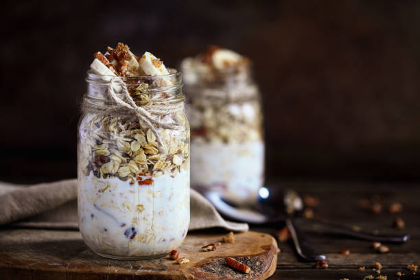 Healthy overnight oatmeal, Bircher muesli, served with bananas, brown sugar, pecan nuts, and maple syrup stock photo