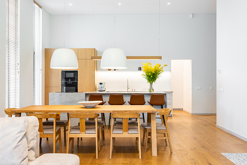 Modern and bright kitchen with large wooden table and chairs in front of it. Spacious.