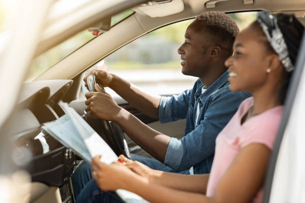 istock Cheerful black lady helping her driving boyfriend, checking map 1342244095