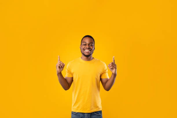 istock Happy Black Man Pointing Fingers Up Showing Something, Yellow Background 1342244131
