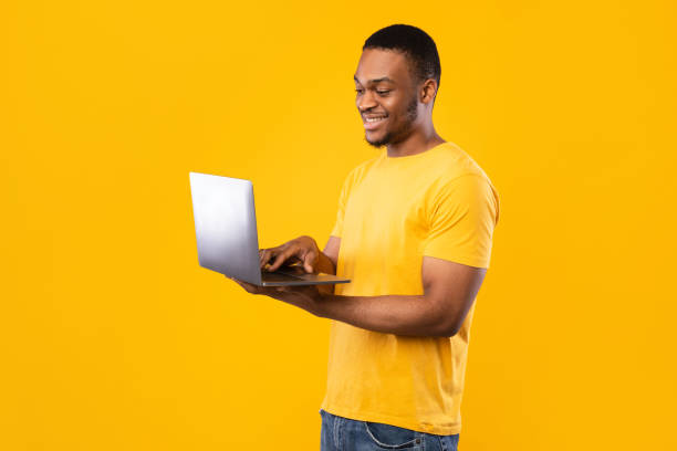 istock Happy African American Freelancer Man Using Laptop Over Yellow Background 1342244165