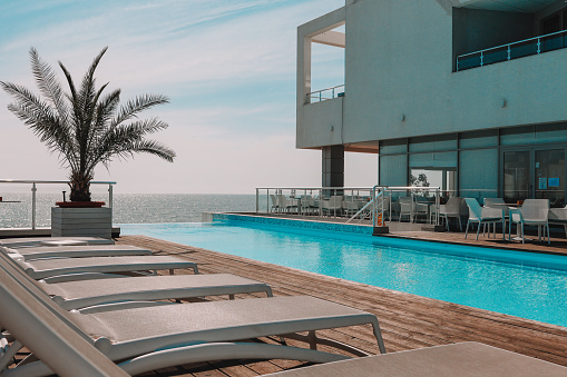 Summer outdoor swimming pool and sun loungers. In the hotel to rest. Seaview landscape.