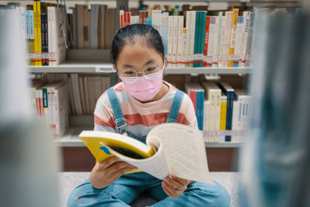 図書館で本棚の本を読む小さな女の子 - bookstore student chinese ethnicity book ストックフォトと画像