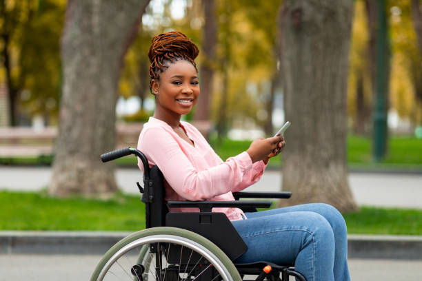 istock Happy disabled black woman in wheelchair using cellphone, checking social media, browsing web at autumn park 1342245779