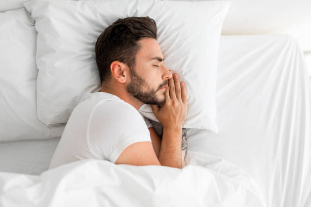 istock Asleep millennial man sleeping, resting peacefully in comfortable bed, lying with closed eyes, top view, free space 1342247144