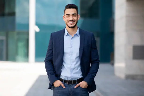 Photo of Handsome middle-eastern guy businessman posing next to office center