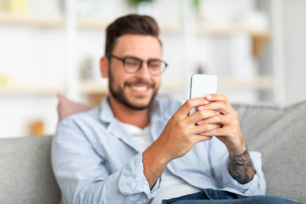 istock Happy millennial guy enjoying video chat with lover, looking at smartphone screen and smiling, free space 1342247187
