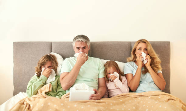 ritratto di famiglia malata con bambini malati a letto - cold and flu flu virus bed couple foto e immagini stock