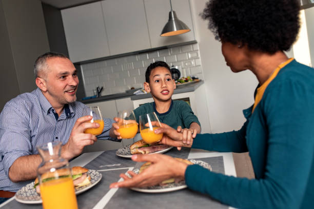 istock Smiling mixed race family sitting at the kitchen table having breakfast at home. 1342248741