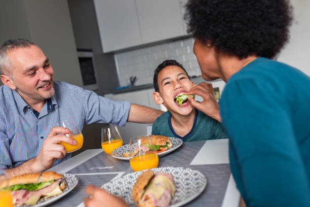 istock Smiling mixed race family sitting at the kitchen table having breakfast at home. 1342248836