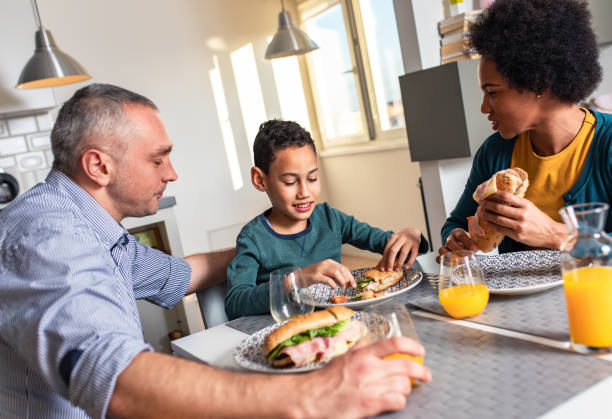 istock Smiling mixed race family sitting at the kitchen table having breakfast at home. 1342248945
